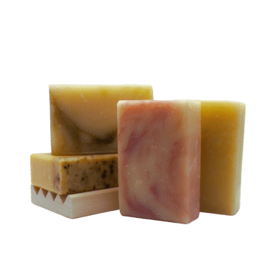 Blossom and Bloom Soap Collection with herbal-infused bars on a natural wood soap dish.