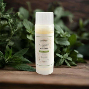 All-natural bug repellent stick on a wooden surface with green leaves in the background
