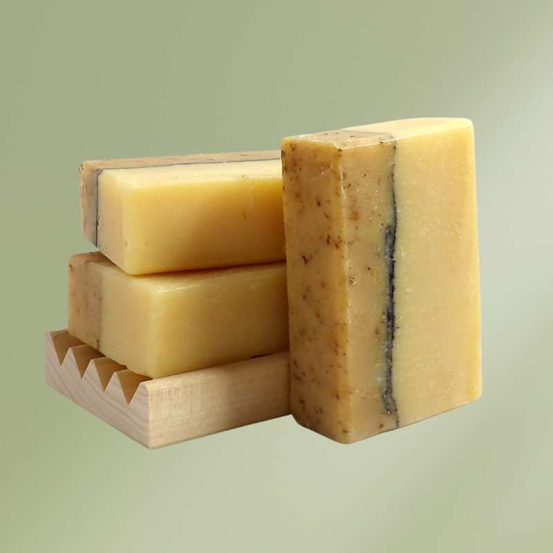 Bar of natural soap with calendula blossoms and packaging box on wooden surface