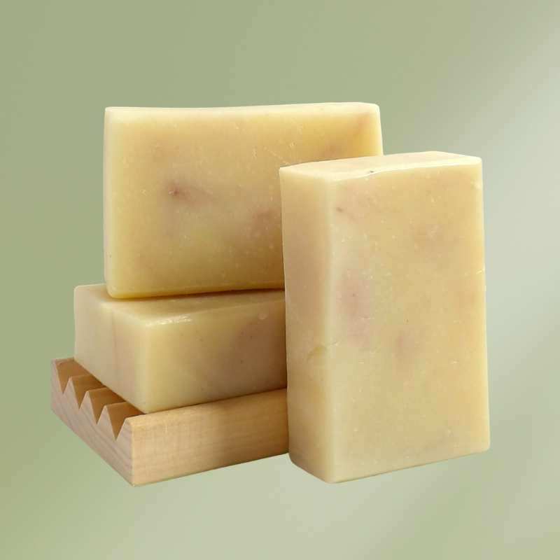 natural soap made with lavender and bergamot essential oils in a white box on a wood shelf with leaves in background